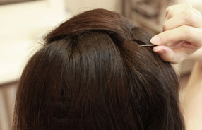 3 再以梳子尾端輕挑中間頭髮，以修飾臉型，扭轉髮束以毛夾固定。